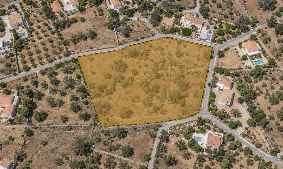 Aerial view of a rustic plot outlined in yellow, surrounded by houses and olive groves